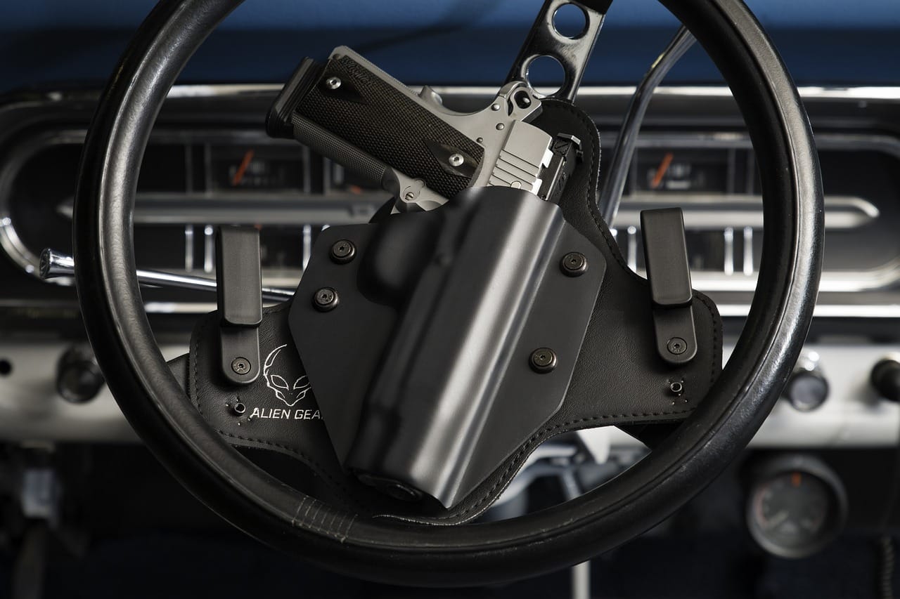 Pistola in una fondina nera agganciata al volante di un'auto d'epoca